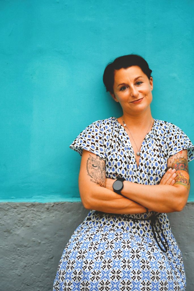 Aline Pelzer angelehnt an türkiser Wand für Gründungszuschuss für virtuelle Assistenten